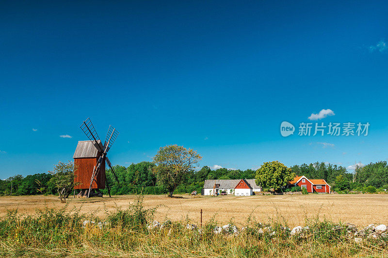 Characteristic landscape on the island of Öland (Sweden) with wooden mill and a farmhouse painted red